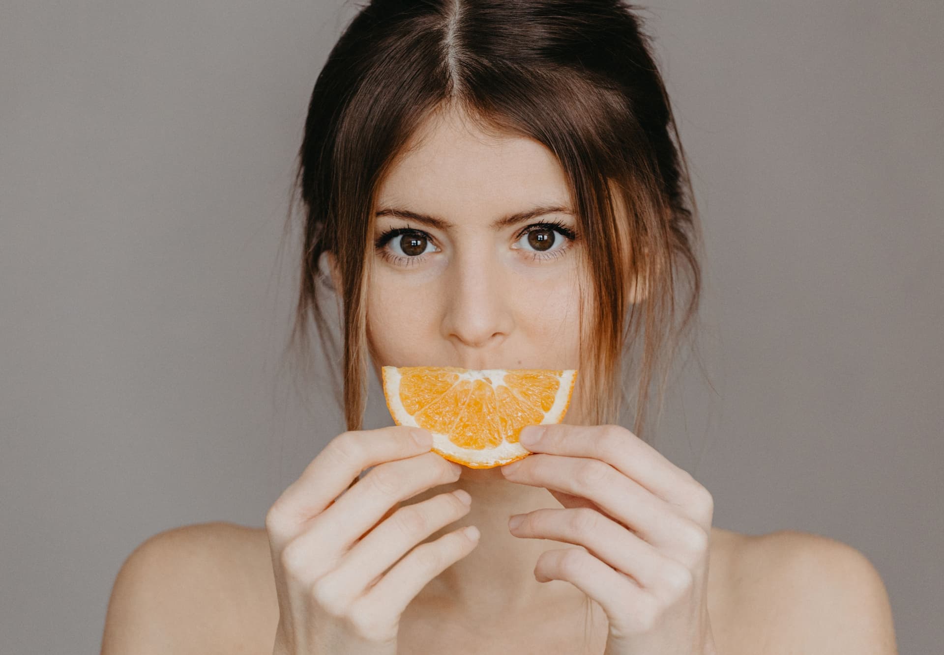 Citrus and a matte dropper bottle on a warm paper-toned surface
